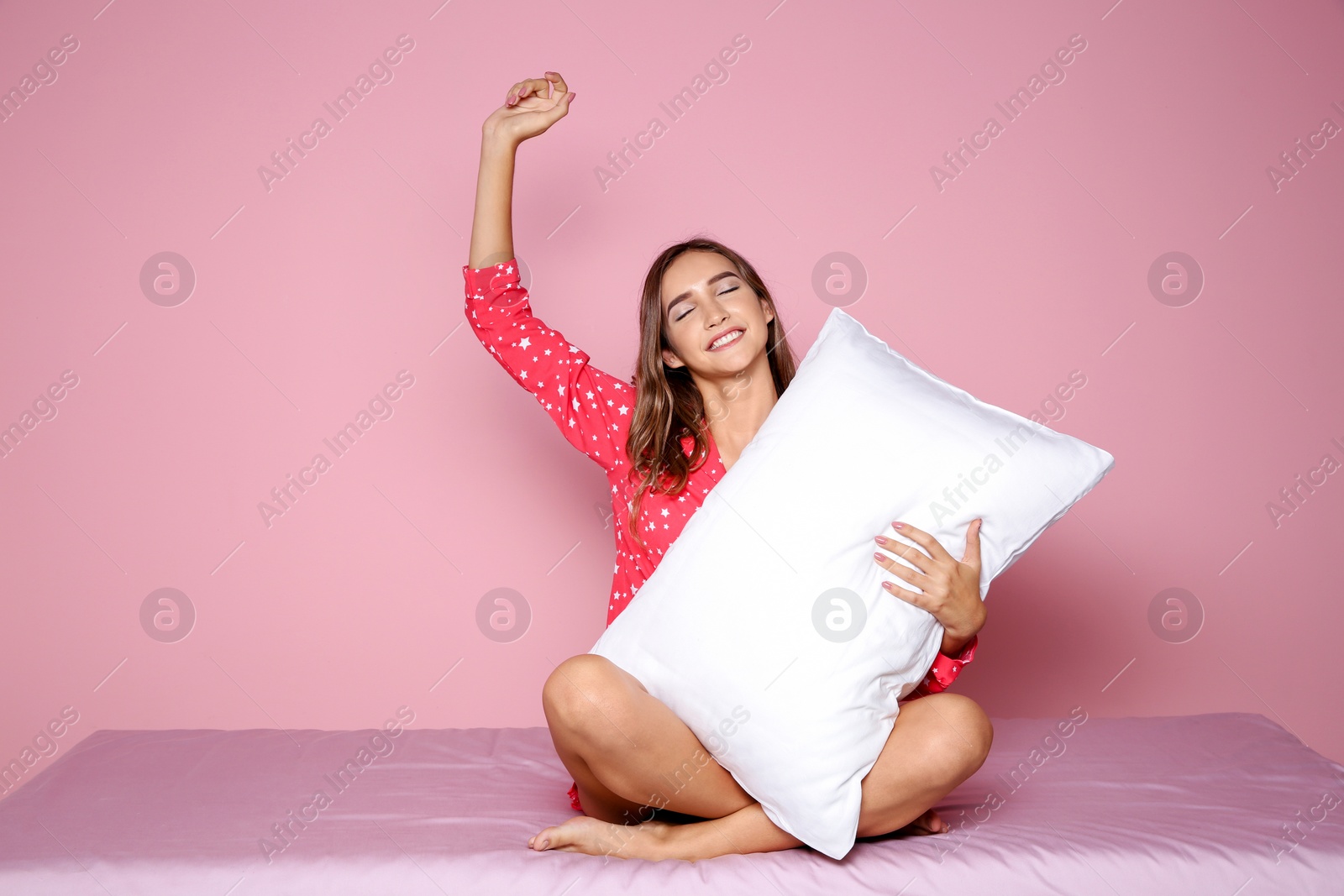 Photo of Beautiful teen girl hugging pillow on bed against color background