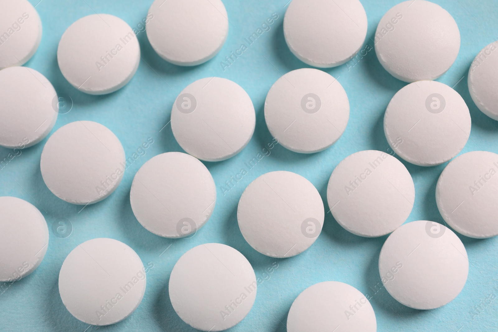 Photo of Many white pills on light blue background, flat lay