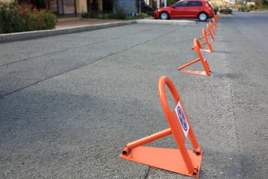 Photo of Many parking barriers with No Stopping signs on asphalt in city. Space for text