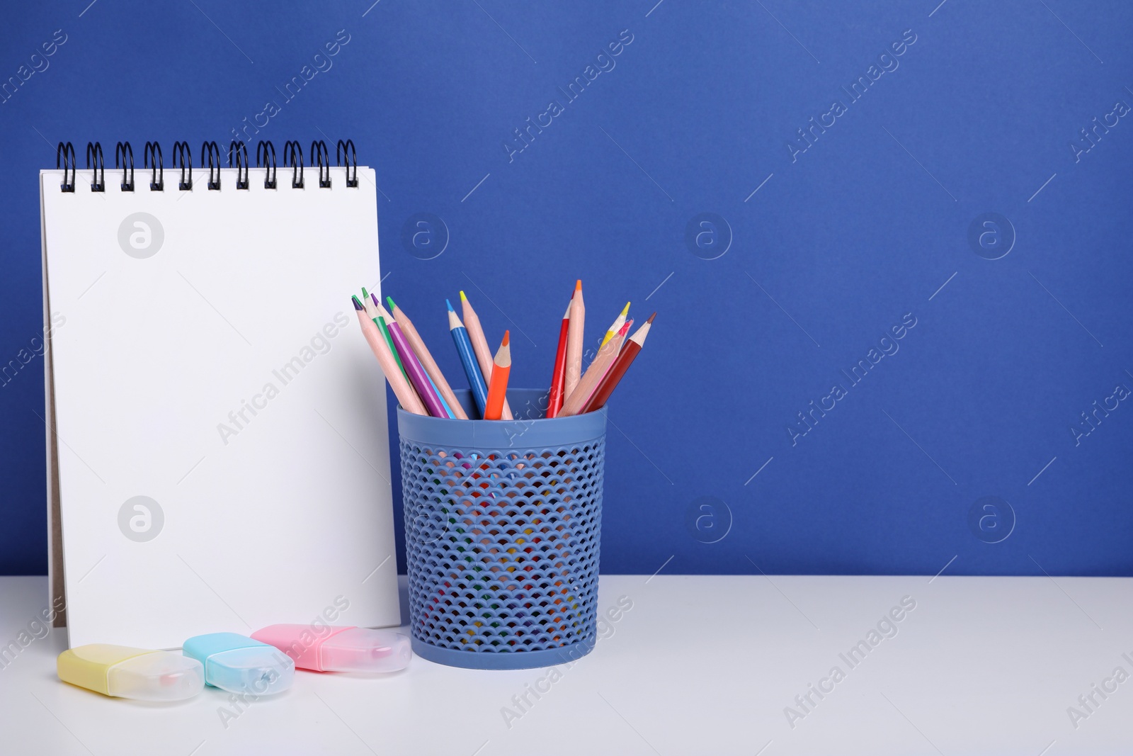 Photo of Different school stationery on white table against blue background, space for text. Back to school