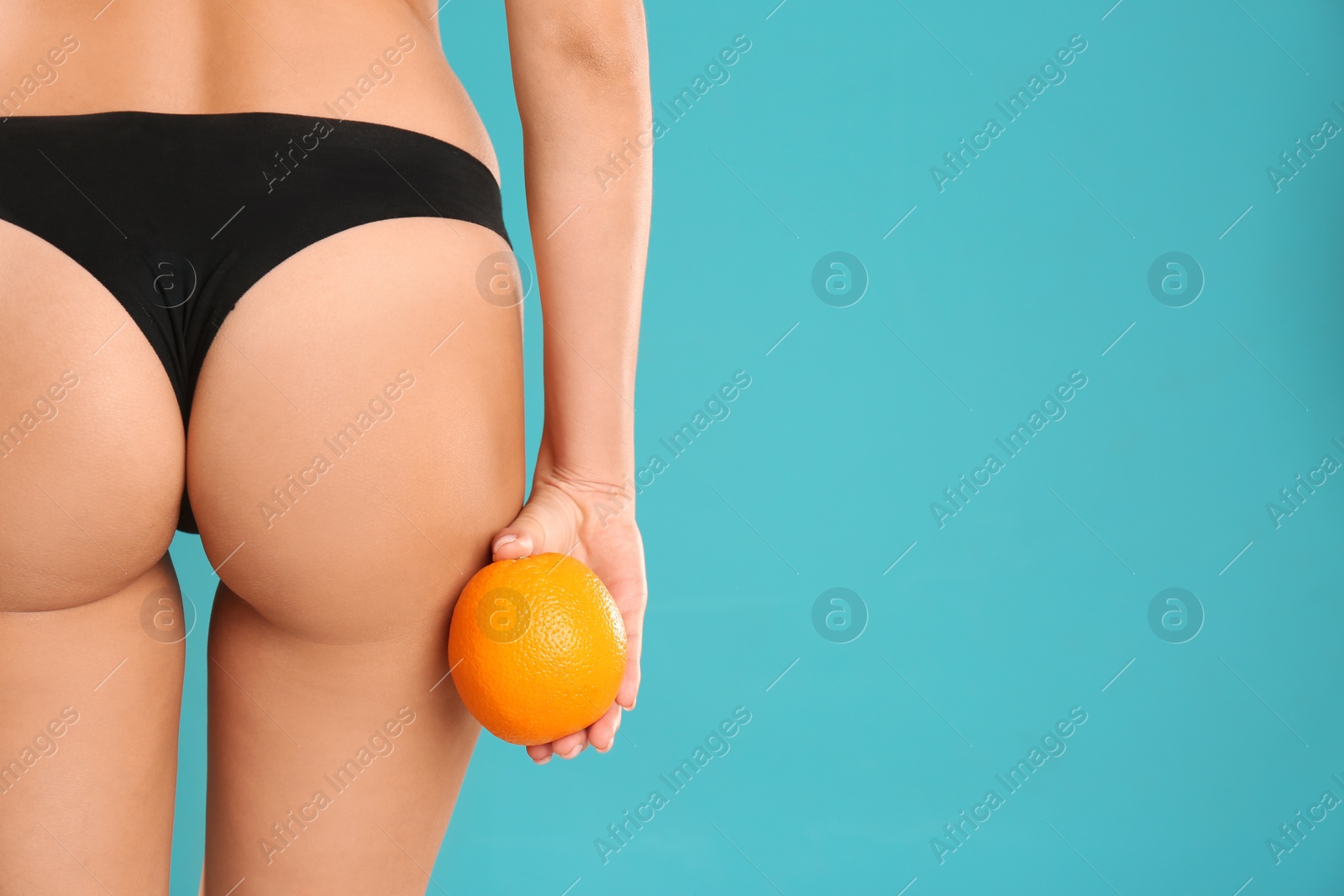 Photo of Closeup view of slim woman in underwear with orange on color background, space for text. Cellulite problem concept