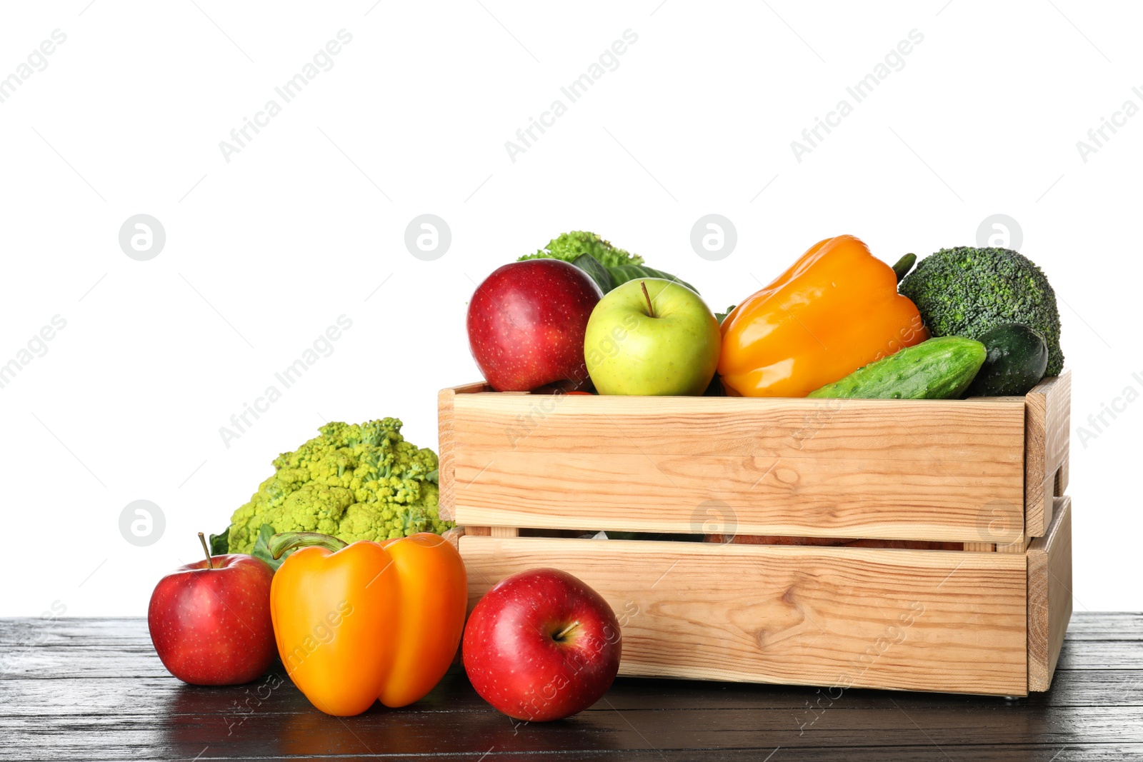 Photo of Wooden crate filled with fresh vegetables and apples on table against white background