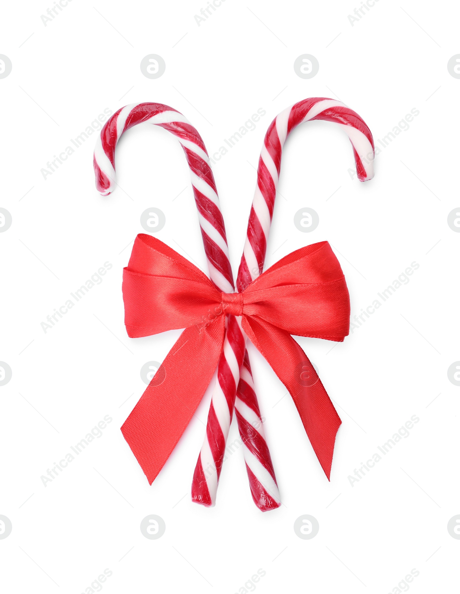 Photo of Sweet Christmas candy canes with red bow on white background, top view