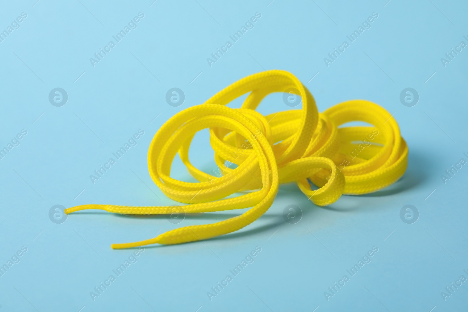 Photo of Yellow shoe lace on light blue background