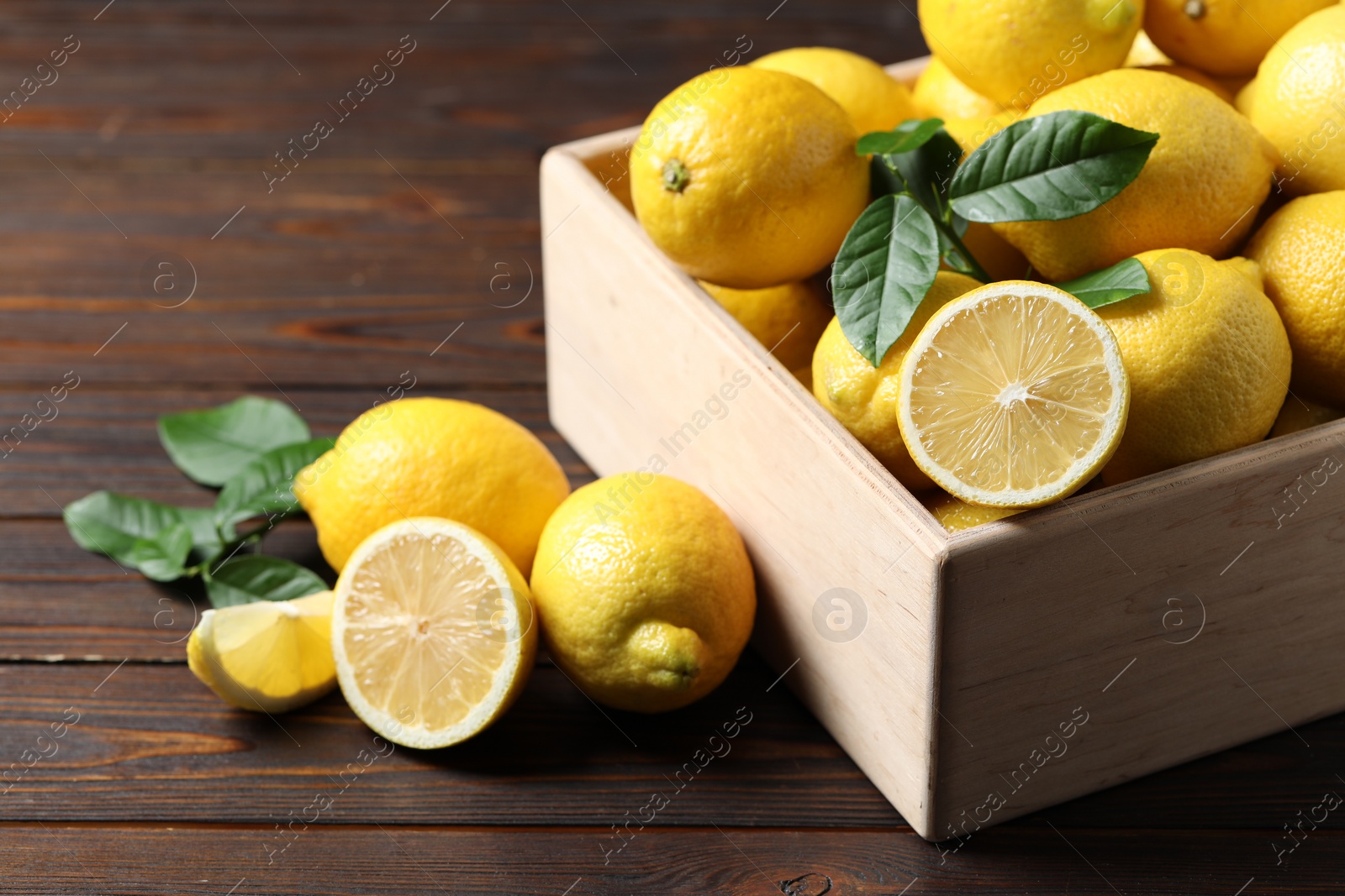 Photo of Fresh lemons in crate on wooden table