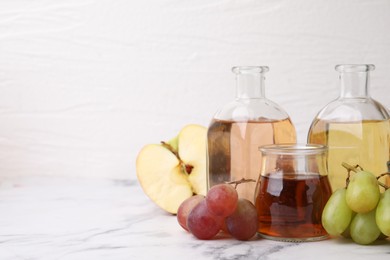 Photo of Different types of vinegar and ingredients on light marble table, closeup. Space for text