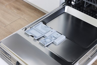 Photo of Open clean empty dishwasher machine indoors, closeup. Home appliance