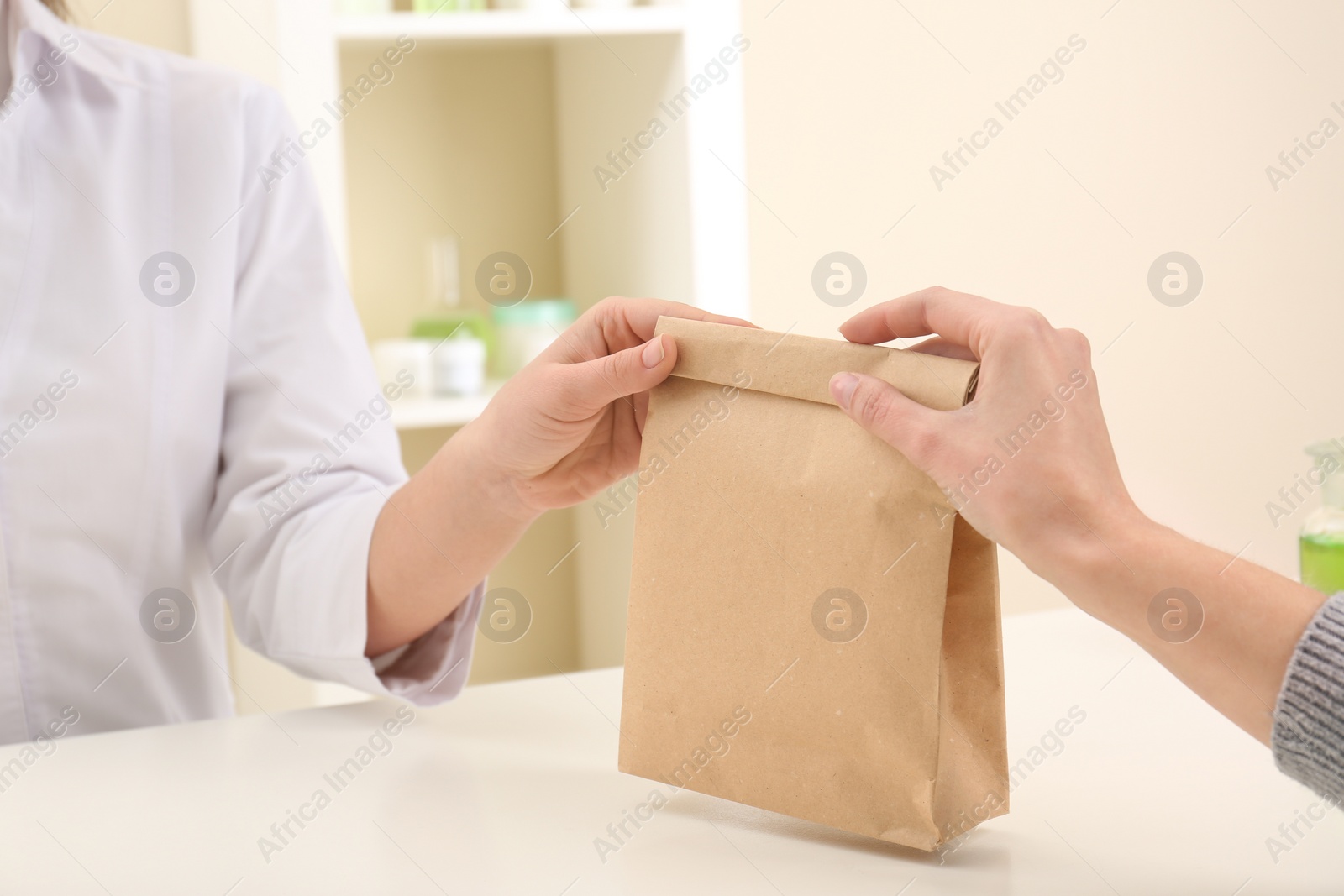 Photo of Woman giving paper bag with order to customer in shop, closeup. Mock up for design