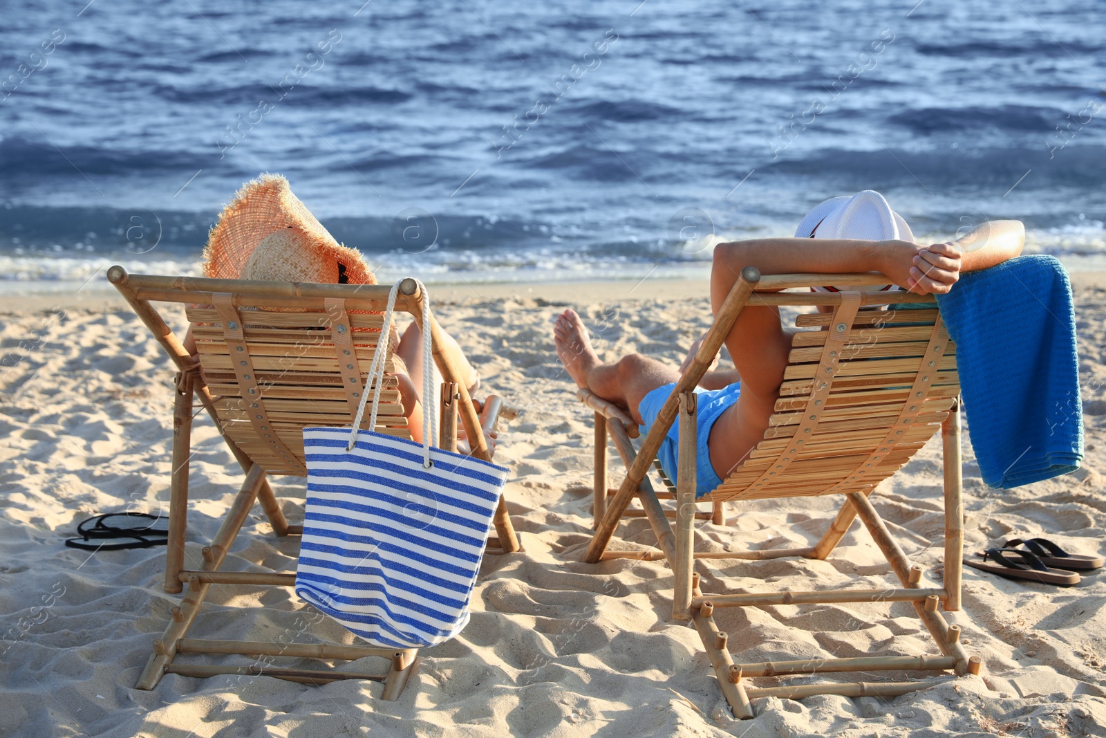 Photo of Young couple relaxing in deck chairs on beach near sea