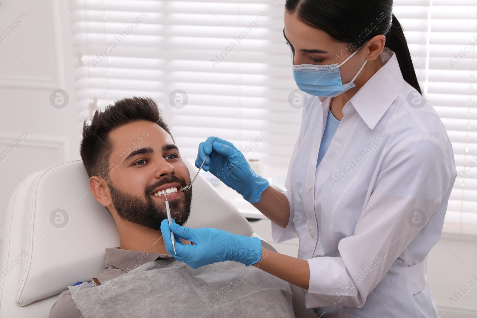 Photo of Dentist examining young man's teeth in modern clinic
