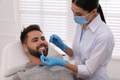 Dentist examining young man's teeth in modern clinic