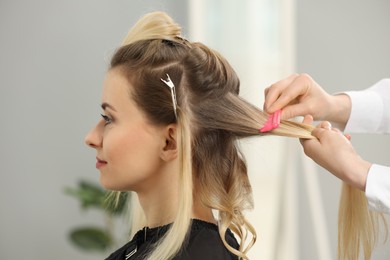 Photo of Hair styling. Professional hairdresser combing woman's hair indoors, closeup