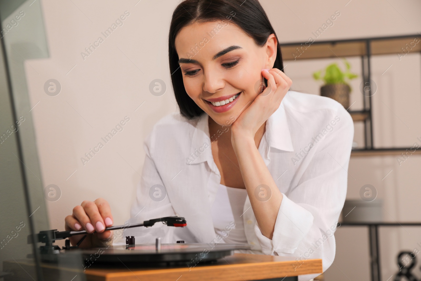 Photo of Happy young woman using turntable at home