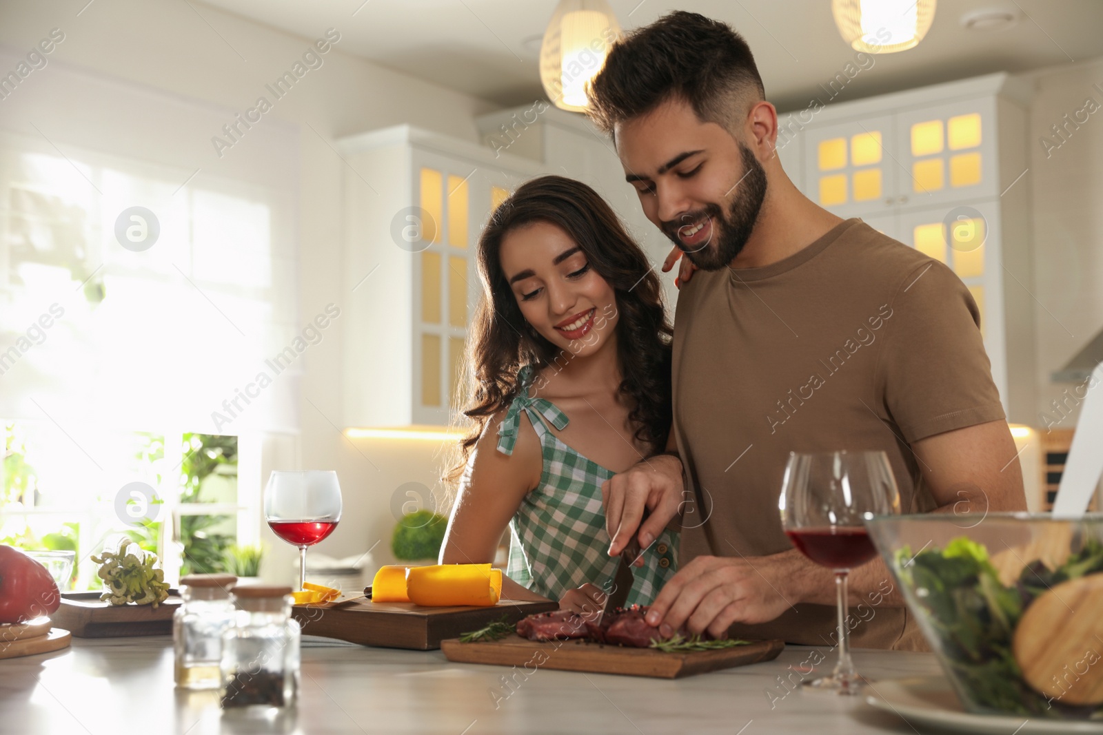 Photo of Lovely young couple cooking meat together in kitchen