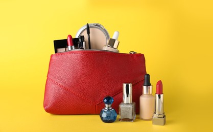 Photo of Cosmetic bag and makeup products with accessories on yellow background