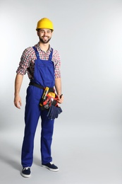 Photo of Full length portrait of construction worker with tool belt on light background. Space for text