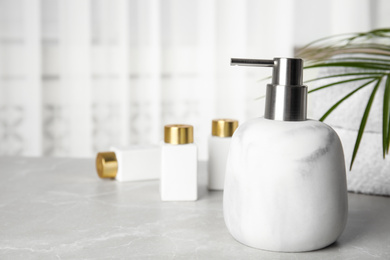 Photo of Modern marble soap dispenser on light table