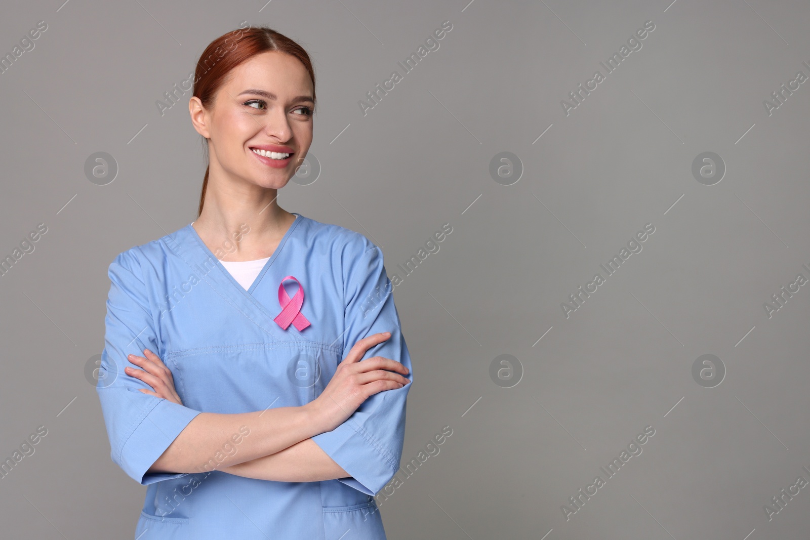 Photo of Mammologist with pink ribbon on gray background, space for text. Breast cancer awareness