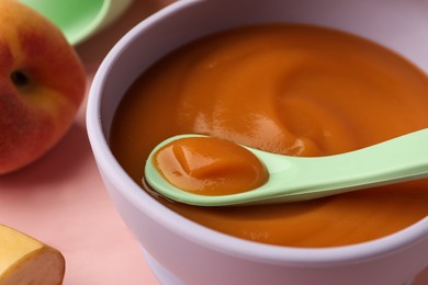 Photo of Healthy baby food in bowl on pink table, closeup