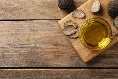 Photo of Glass bowl of truffle oil with board on wooden table, flat lay. Space for text