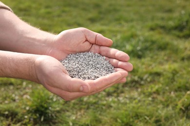 Photo of Man with fertilizer in hands outdoors, closeup