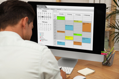 Man using calendar app on computer in office, closeup