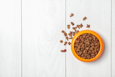 Bowl with food for cat or dog on wooden background. Pet care