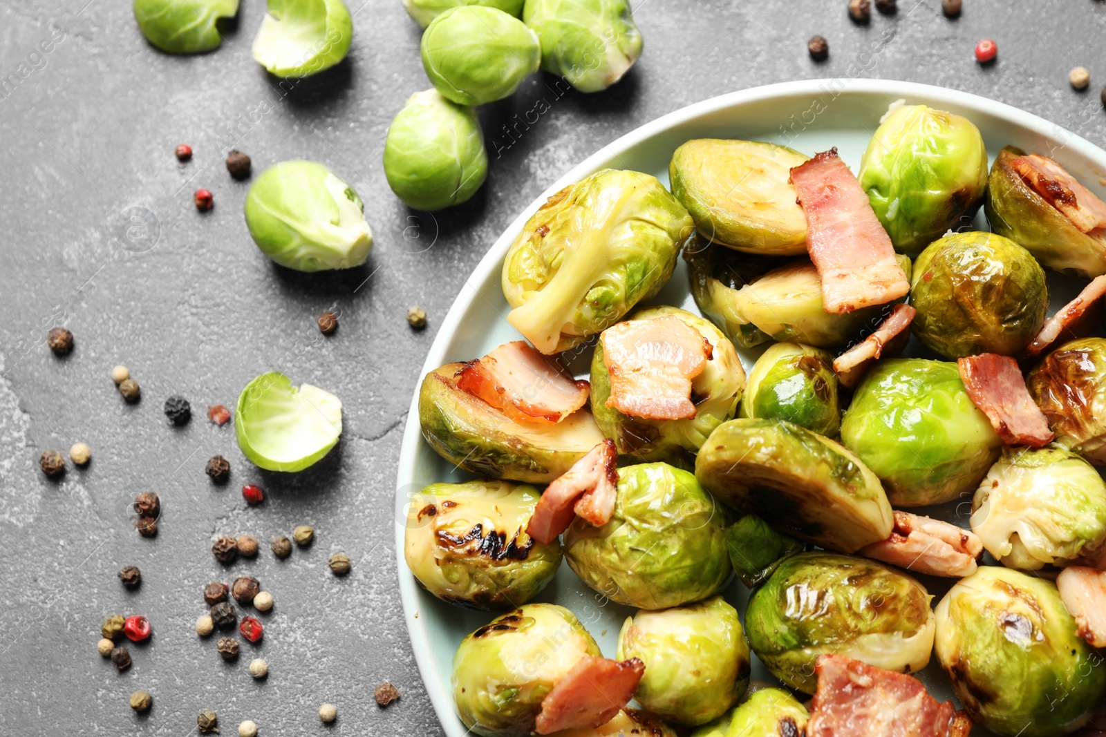 Image of Delicious fried Brussels sprouts with bacon on grey table, flat lay