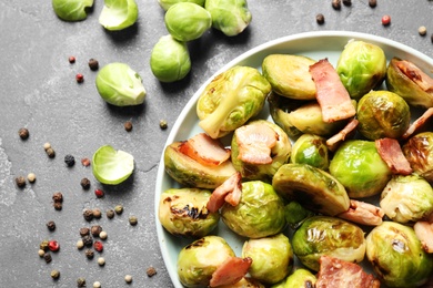 Image of Delicious fried Brussels sprouts with bacon on grey table, flat lay