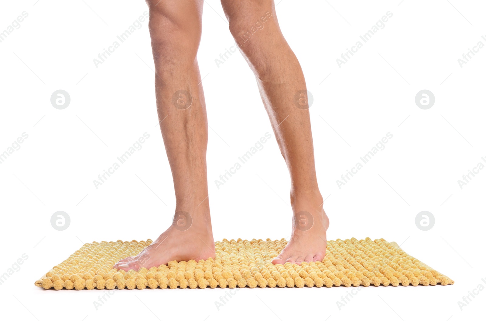 Photo of Man standing on soft yellow bath mat against white background, closeup