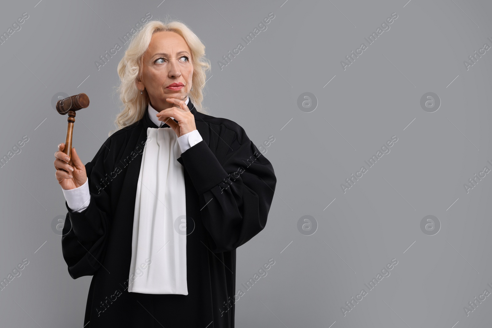 Photo of Senior judge with gavel on grey background. Space for text