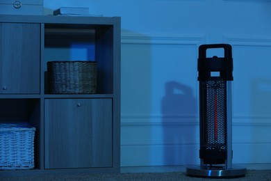 Photo of Electric infrared heater in dark room at night