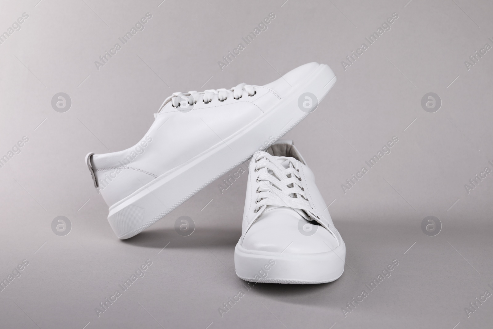 Photo of Pair of stylish white sneakers on grey background