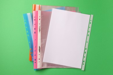 Photo of File folders with punched pockets on green background, flat lay