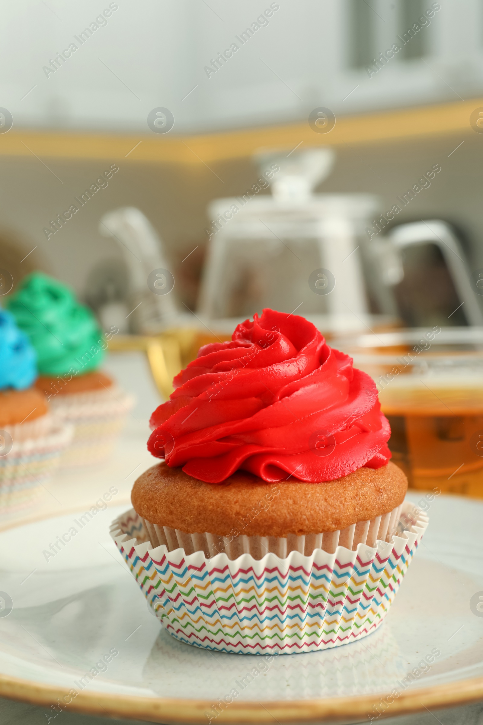 Photo of Delicious cupcake with red cream on plate, closeup