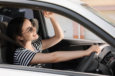 Photo of Listening to radio while driving. Beautiful young woman with stylish sunglasses enjoying music in car