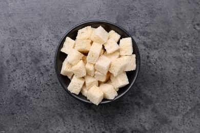 Photo of Crispy rusks in bowl on grey table, top view