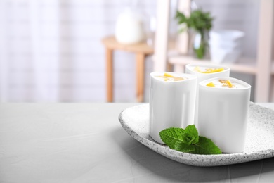 Photo of Plate with cups of peach yogurt on table indoors, space for text. Multi cooker recipe