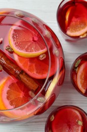 Photo of Glasses and bowl with aromatic punch drink on white wooden table, flat lay