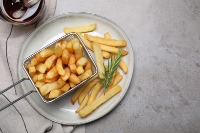 Photo of Tasty french fries with rosemary and soda drink on light grey table, flat lay. Space for text