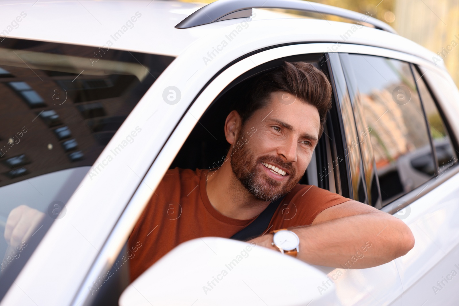 Photo of Happy man looking out of car window, view from outside. Enjoying trip
