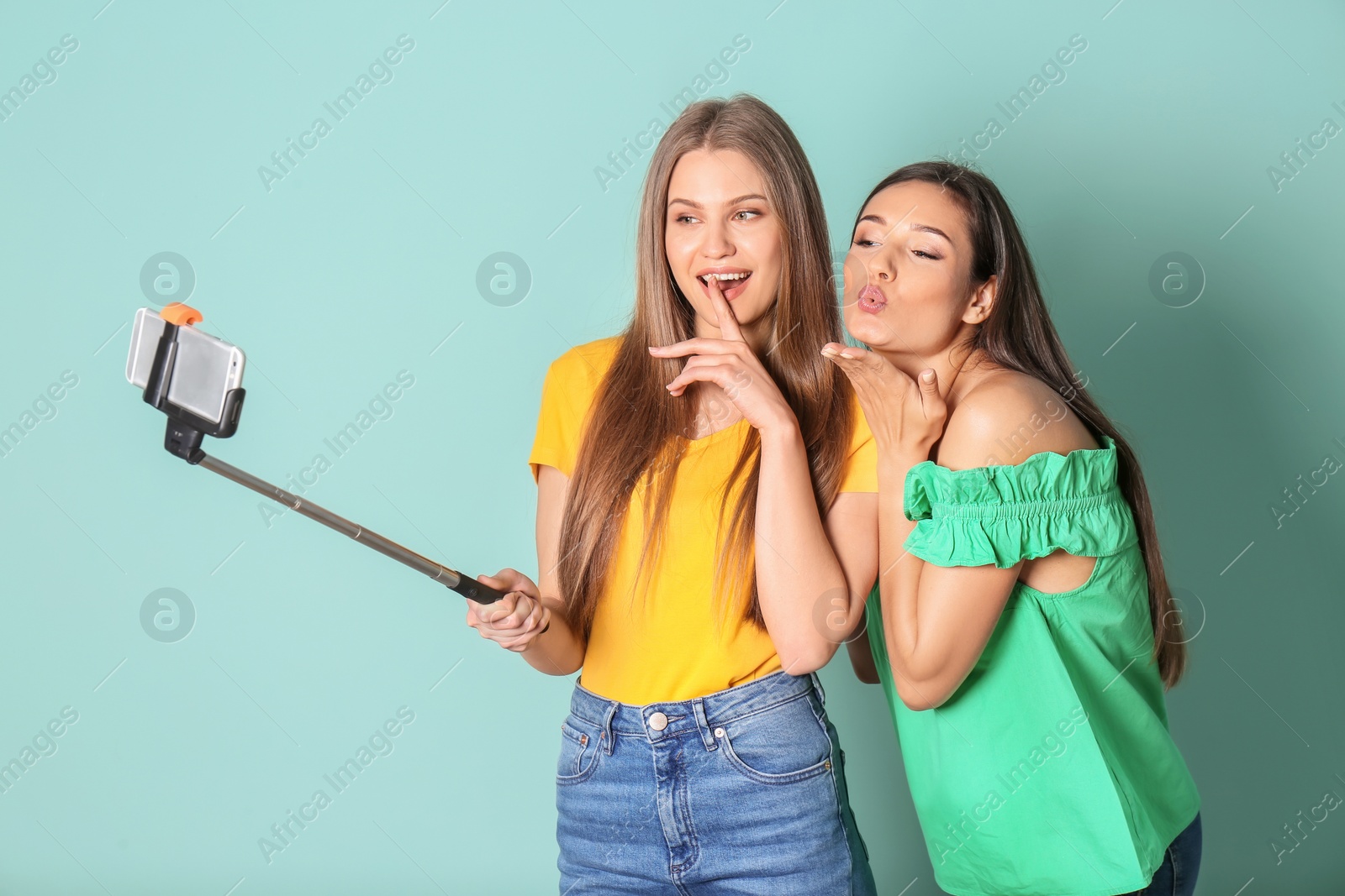 Photo of Young beautiful women taking selfie against color background