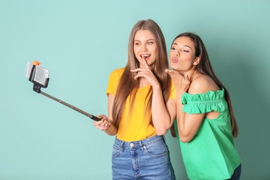 Young beautiful women taking selfie against color background