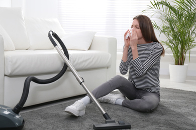 Photo of Young woman suffering from dust allergy while vacuuming house