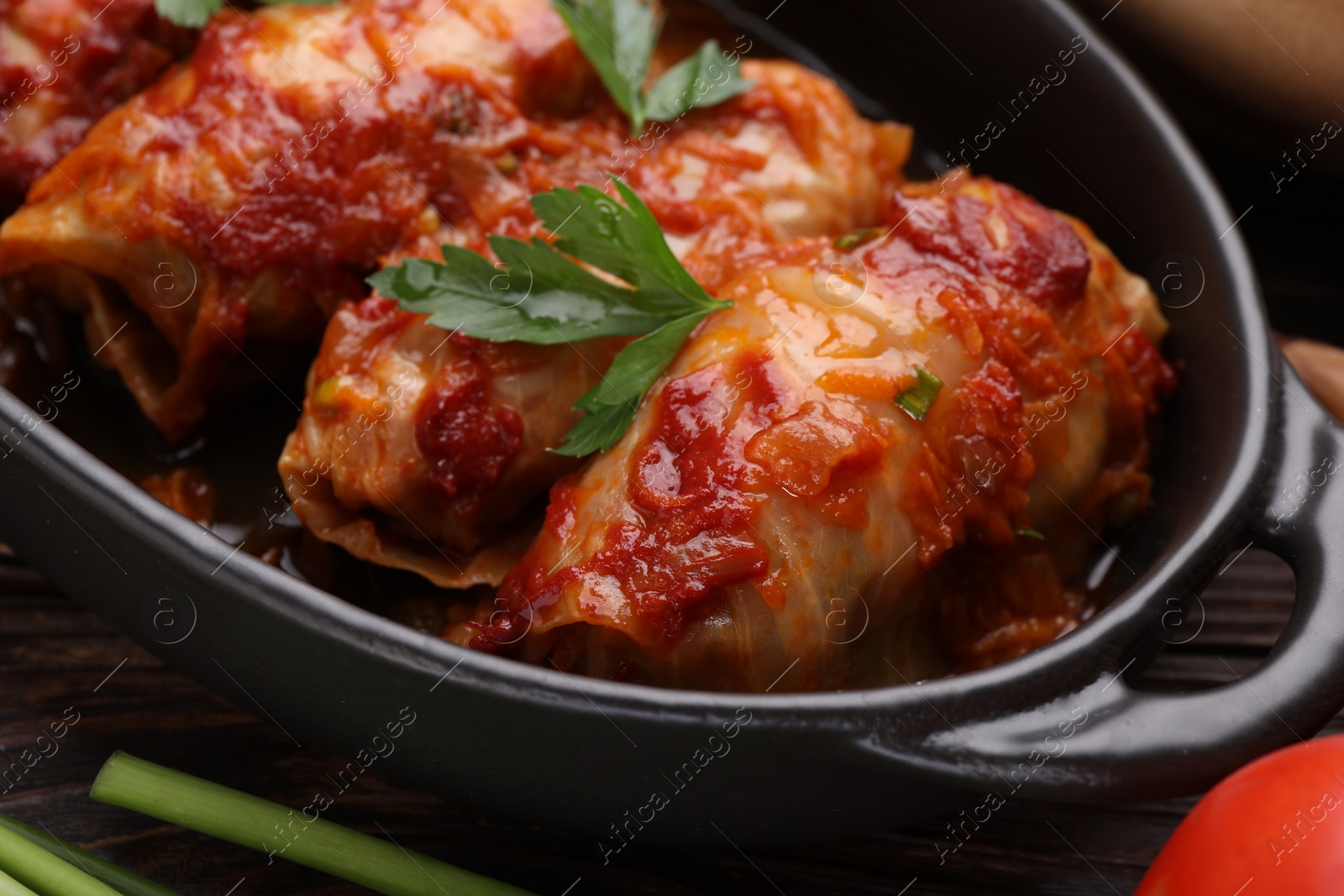 Photo of Delicious stuffed cabbage rolls cooked with homemade tomato sauce on table, closeup