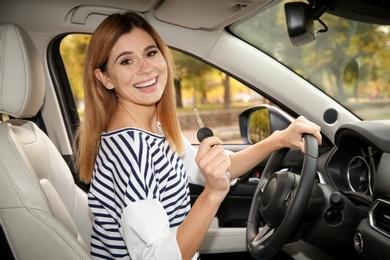 Photo of Happy woman holding car key in auto. Driving license test