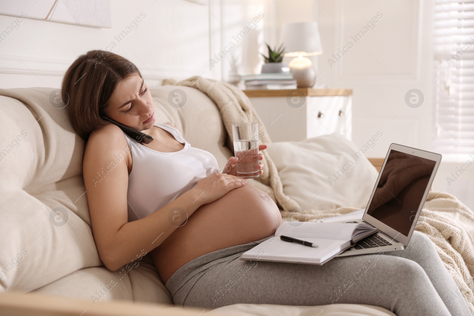 Photo of Tired pregnant woman working on sofa at home. Maternity leave