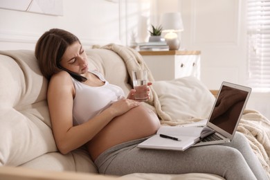 Tired pregnant woman working on sofa at home. Maternity leave