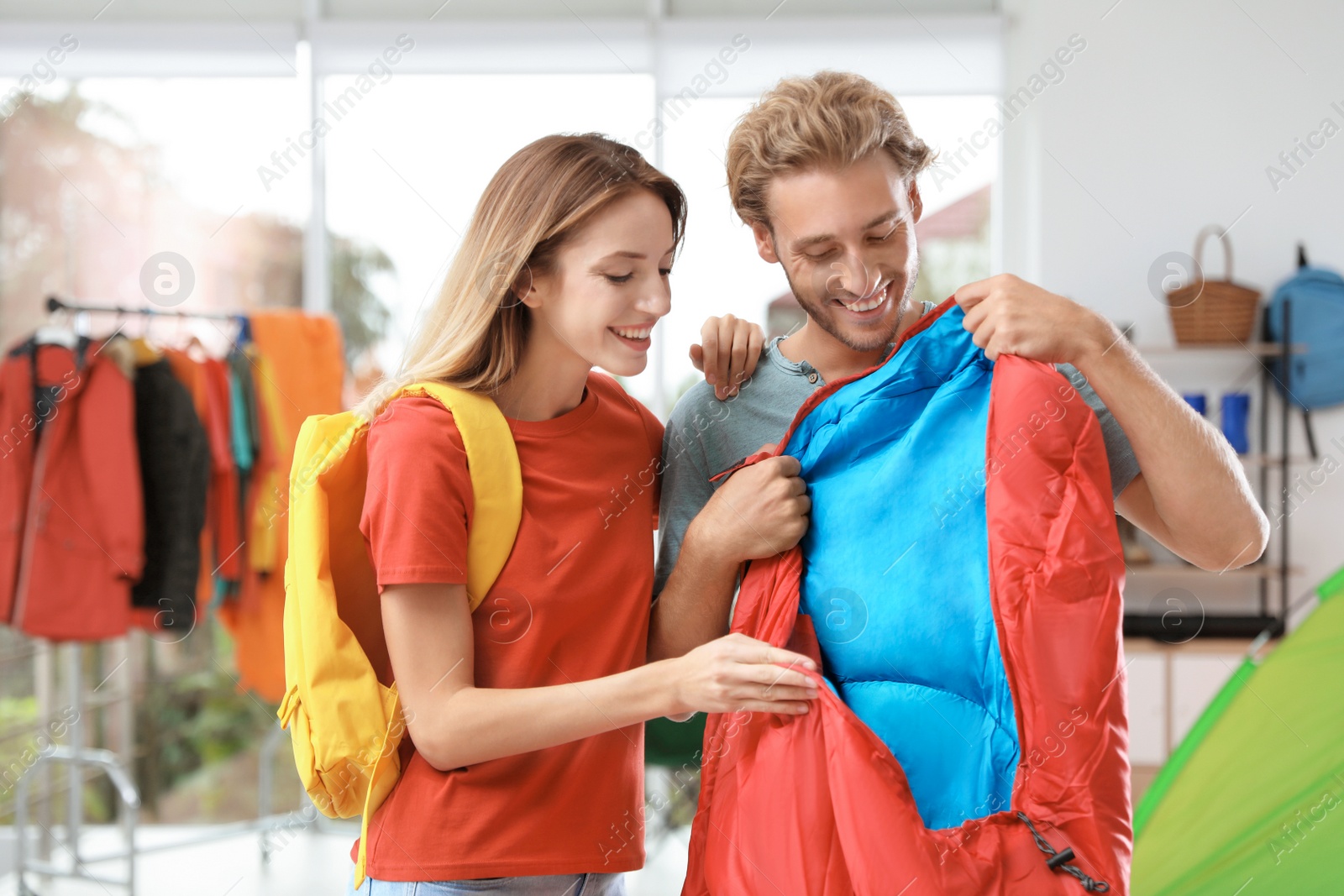 Photo of Young couple choosing sleeping bag in store