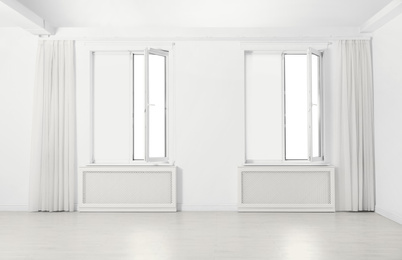 Photo of Windows with elegant curtains and blinds in empty room